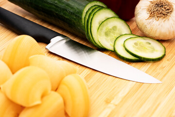Chopped cucumber on wooden cutting board with knife