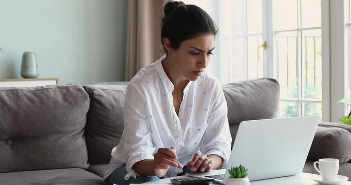 Indian woman sit on sofa sorting out papers, calculate monthly expenses feels stressed, facing financial problems, lack of money pay utility household or rental payment. Bankruptcy accounting, concept