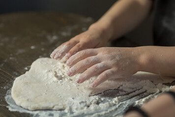 Obraz premium children's hands make dough on the table close-up.