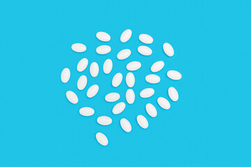White pills for treatment with bottle on blue background, pharmacy and medicine concept, top view