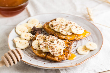 Ready to eat bruschettas with honey, banana and chocolate on a plate on the table. Vegetarian homemade snack. Close-up