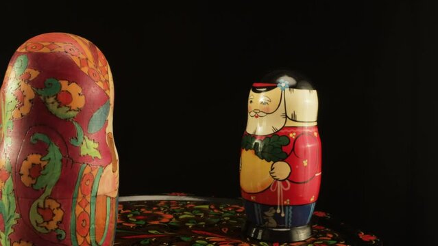 Nesting dolls depicting two old men and a granddaughter. A group of dolls on a Zhostovsky dish