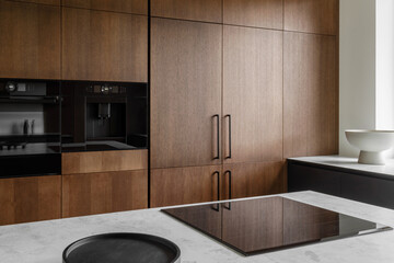 Modern minimalistic kitchen with black and wooden surfaces, marble kitchen island top and household...