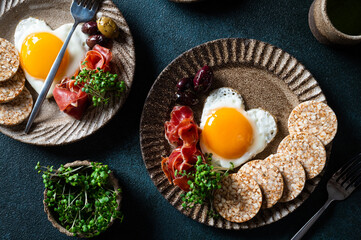 Romantic breakfast - fried eggs in the shape of a heart and olives. Healthy breakfast. Rice cakes with eggs and hamon. Keto diet breakfast. Top view.
