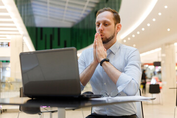 Young businessman practicing breathing exhalation exercises working online to manage stress and...