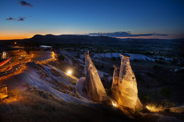 Fairytale chimneys and viewpoint in Cappadocia illuminated by artificial light at sunset