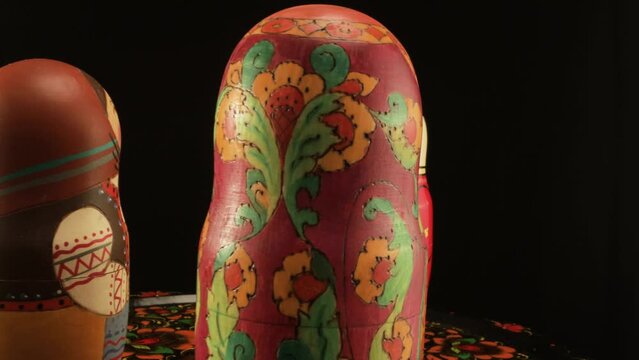 Nesting dolls depicting an old man and granddaughter greeting a guest. The stand is a Zhostov dish