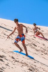 Fototapeta premium Caucasian youth sliding on a board in the sand