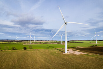 Aerial shot of wind farm turbines with blue cloudy sky, UK