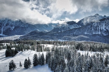 Wetterstein - winter landscape with snow covered mountains, forest and clouds in the sky