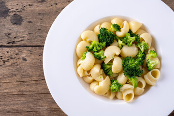 pasta with broccoli on a white plate and wooden table