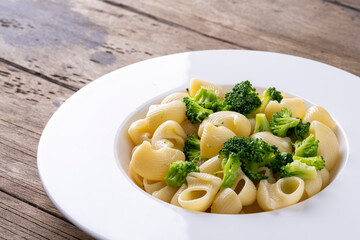 pasta with broccoli on a white plate and wooden table