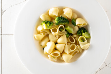 pasta with broccoli on a white plate and white ceramic background.