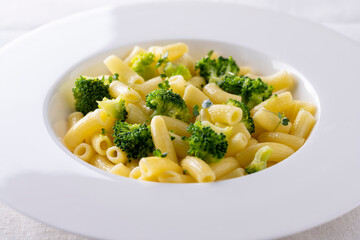 pasta with broccoli on a white plate and white ceramic background.