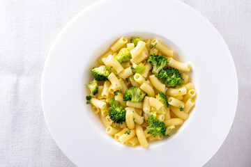 pasta with broccoli on a white plate and white ceramic background.