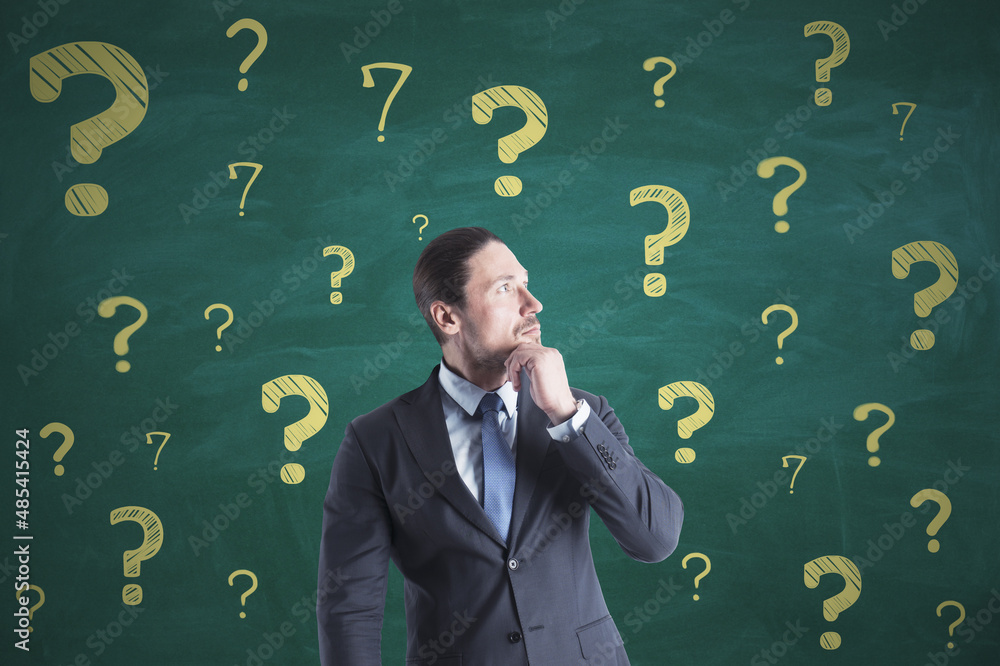Poster portrait of attractive thoughtful young european businessman on chalkboard wall background with ques