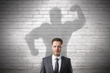Abstract image of attractive european businessman with strong muscle shadow on brick wall...