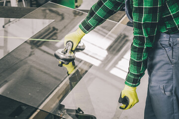 A specialist in a glass company removes a large pane of glass from the table using a specialized...