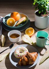 Healthy breakfast. Croissant, donut, coffee, jam, fruits: oranges and pears.