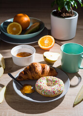 Healthy breakfast. Croissant, donut, coffee, jam, fruits: oranges and pears.