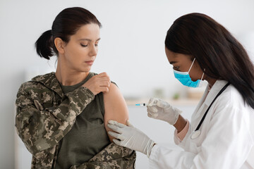 African American Nurse Making Vaccine Injection Shot To Young Soldier Woman