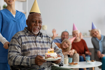 Black man in wheelchair celebrating birthday at nursing home - Powered by Adobe