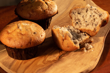 Home nade muffins with blueberries on wooden chopping board.