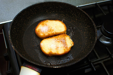 Fried pieces of white bread with sugar in a frying pan.