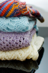Stack of cozy knitted autumn and winter sweaters on a neutral background. Concept of warmth and comfort clothes. Vertical photography.