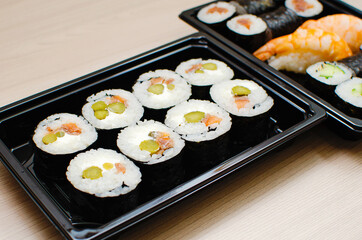 Different sushi and rolls in a plastic container, food delivery.