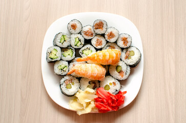 Tiger shrimp sushi and a set of different rolls on a white plate. White and red pickled ginger. Catering, various kinds of sushi rolls. top view flat lay.