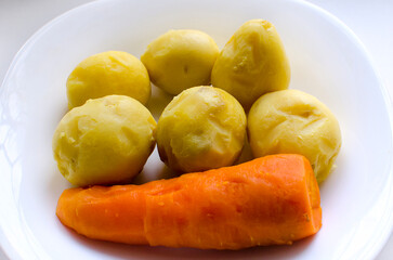 Naklejka na ściany i meble Boiled peeled potatoes and carrots on a white plate.