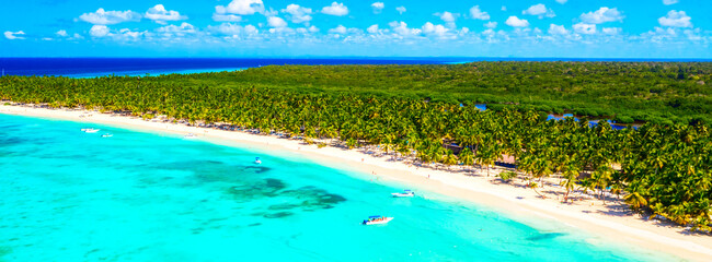 Paradise tropical island nature background. Top aerial drone view of beautiful beach with turquoise sea water, boats and palm trees. Saona island, Dominican republic.