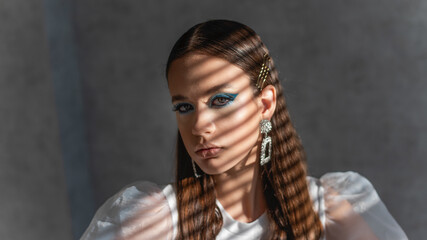 Close-up beauty portrait of girl, clean skin. Light shadow stripes pattern on face. Gray background