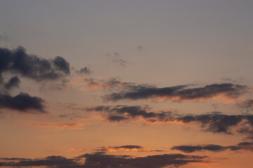 Blurred dark clouds illuminated by the orange sun in the setting.