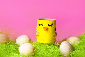 Easter chick craft from paper tube. Kids DIY home activities. Handmade cute toy on pink background. Reuse concept