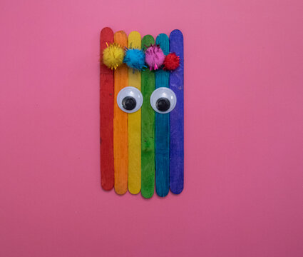 Brightly colored Popsicle sticks glued together, with googly eyes and pom pom balls
