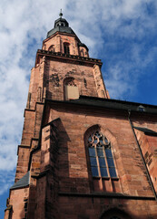 The Facade Of The Cathedral's Bell Tower In Heidelberg Germany On A Beautiful Sunny Summer Day With A Clear Blue Sky And A Few Clouds