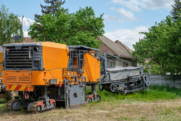 Fototapeta na wymiar Industrial pavement machine parked on the grass