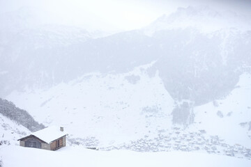 Chalet sous une chute de neige en montagne