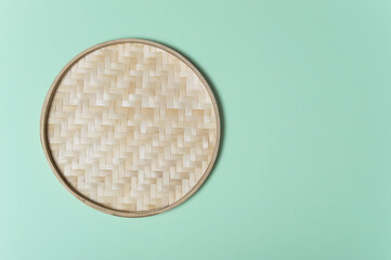 Round empty wicker straw basket with handles on light green background. View from above. Decorative interior items. copy space. Pastel soft colors