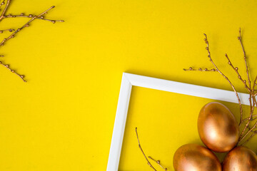 Golden Easter eggs and golden branches on a yellow watercolor background. Banner. Layflat. Space for text 