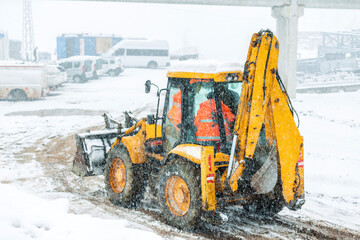 View of a backhoe loader and snowy day in the construction site. It also called a loader backhoe, digger in layman's terms, or colloquially shortened to backhoe within the industry.