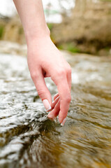 hand touches the water of a mountain river