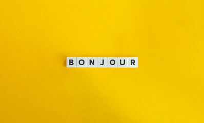 Bonjour word on letter tiles on yellow background. Minimal aesthetics.