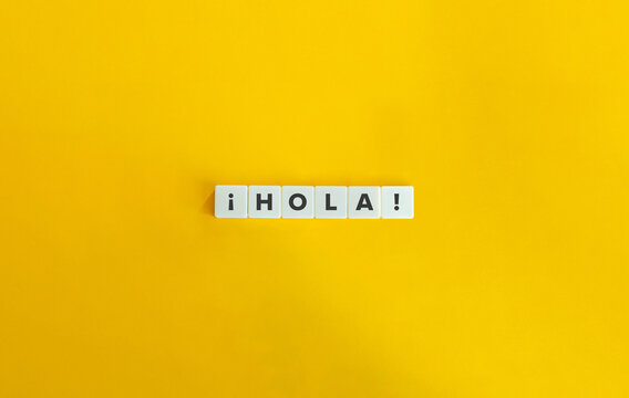 Hola word on letter tiles on yellow background. Minimal aesthetics.