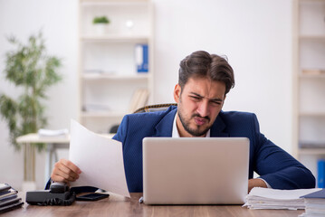 Young male employee unhappy with excessive work in the office