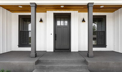Front door to modern farmhouse home. Home exterior with white vertical wood siding and black front...