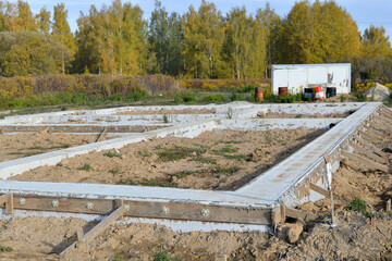 Fototapeta na wymiar The foundation of a poured concrete solution of a country house in close-up at the beginning of construction against the background of a forest. Background