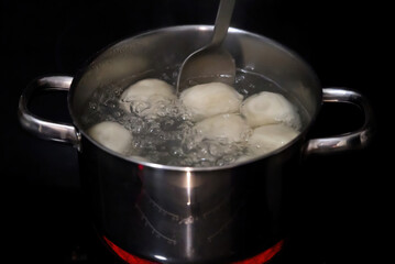 cooking the khinkals in boiling water. Boiled khinkali in a pan. the cook mixes the dumplings with a spoon in a pot. close up
